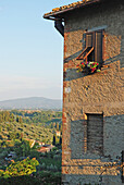 Eine Außenwand eines Gebäudes mit einem offenen Fensterladen und einem Blumenkasten; San Gimignano Toskana Italien