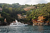 Eine im Wasser ankernde Yacht mit Wohngebäuden am Wasser; Italien
