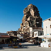A Large Rock Formation (Castle Of Ortahisar) Against A Blue Sky In An Urban Area; Ortahisar Nevsehir Turkey
