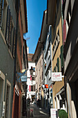 Ein schmaler Gang zwischen Gebäuden mit an den Wänden befestigten Ladenschildern; Zürich Schweiz
