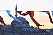 Rote und weiße Stofffahnen wehen mit der Rustem-Pascha-Moschee im Hintergrund bei Sonnenuntergang; Istanbul Türkei