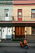 Orange Motor Scooter Parked In Front Of A Residential Building; Montreal Quebec Canada