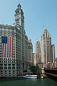 Amerikanische Flagge an der Seite eines Gebäudes mit einem Uhrenturm entlang des Chicago River; Chicago Illinois Vereinigte Staaten von Amerika