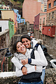 Mexico, Guanajuato State, Guanajuato, Two young women hugging and laughing in downtown area
