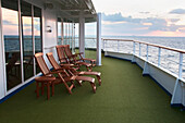 Hölzerne Liegestühle auf dem Deck eines Kreuzfahrtschiffes bei Sonnenuntergang; Tokio, Japan