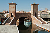 Steinerne Brücke mit Türmen und Stufen, die sich im Wasser spiegeln; Comacchio, Emilia-Romagna, Italien