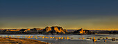 Vereinigte Staaten von Amerika, Felsen im Wasser und Sonnenlicht, das die Uferlinie bei Sonnenuntergang am Powell River beleuchtet; Utah