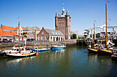 Netherlands, Zealand, Boats in the harbor with buildings by the waterfront; Zierikzee