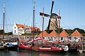 Netherlands, Zealand, Boats docked in the harbor with a windmill in the background; Zierikzee