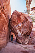 Jordan, Tourist walking under boulder; Petra