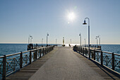 People On A Promenade Leading Out To The Water On A Sunny Day; Viareggio, Tuscany, Italy