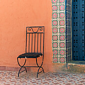 Ein schwarzer Metallstuhl steht vor einer bunten Wand; Talouste, Souss-Massa-Drass, Marokko