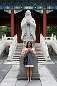 Eine Frau steht vor einer Konfuzius-Statue im Konfuzius-Tempel; Peking, China