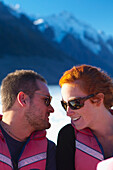 Ein Paar teilt einen Moment, während sie eine Bootsfahrt durch einen See am Fuße des Mount Cook machen; Neuseeland