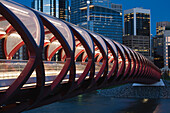 Rote Brücke bei Nacht mit Lichtern und Stadtgebäuden im Hintergrund; Calgary, Alberta, Kanada