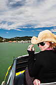 Ein Mädchen hält ihren Cowboyhut auf einer Bootsfahrt von Russell nach Paihia; Neuseeland