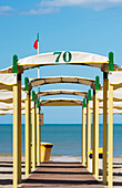Eine gelbe und grüne Struktur über einem Gehweg, der zum Strand und zur Adria führt; Rimini, Emilia-Romagna, Italien