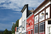 Bunte alte hölzerne Ladenfront mit Wolken und blauem Himmel; Dawson City, Yukon, Kanada