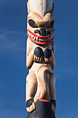 An Animal Carved And Painted On A Wooden Totem Pole Against A Blue Sky; Whitehorse, Yukon, Canada