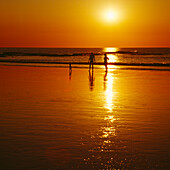 Menschen am Strand bei Sonnenuntergang