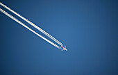Airplane and contrails against blue sky, Canada