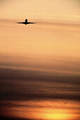 Flugzeug fliegt bei Sonnenuntergang