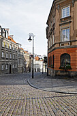Alte Gebäude und Laternenmasten an einer Straßenecke mit Kopfsteinpflaster, Altstadt, Warschau, Polen.