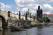 Charles Bridge crossing the Vltava River with the Old Town Bridge Tower and Church of St Francis Seraphinus, Prague, Czech Republic.