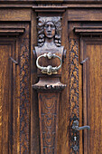 Nahaufnahme eines Türklopfers an einer dekorativen, geschnitzten Holztür, Cesky Krumlov, Tschechische Republik.