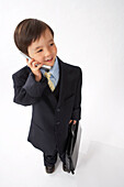 Kleiner Junge als Geschäftsmann verkleidet telefoniert mit Handy