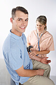 Krankenschwester prüft Blutdruck eines Mannes