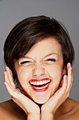 Head and Shoulders Portrait of Mid-Adult Woman Laughing with Grey Background