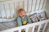 Smiling baby with down syndrome in cot