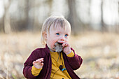 Toddler holding fallen leaf in mouth
