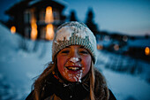 Fröhliches Mädchen in Schnee gehüllt schaut in die Kamera