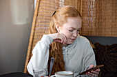 Junge Frau telefoniert und schaut in die sozialen Medien im Cafe