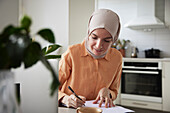 Lächelnde Frau mit Hijab arbeitet zu Hause