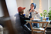 Mutter mit Hidschab hilft Sohn bei den Hausaufgaben