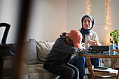 Mother wearing hijab helping tired son with ADD or ADHD doing homework