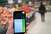 Hand hält Taschenrechner im Supermarkt