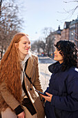 Female friends listen to music or podcast while sharing in-ear headphones