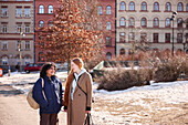 Female friends talking together outdoors in city surroundings