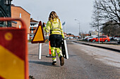 Straßenbauarbeiterin trägt Straßenschild