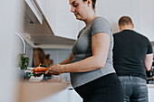 Schwangere Frau schält Gemüse in der Küche