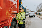 Porträt eines weiblichen Bauarbeiters, der neben einem Lastwagen steht