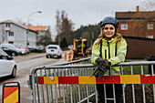 Porträt einer Straßenbauarbeiterin, die sich an eine Verkehrsabsperrung lehnt