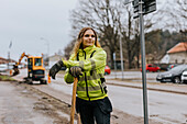 Female road worker leaning on shovel