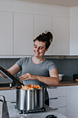 Smiling woman in kitchen preparing food