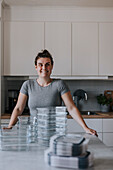 Lächelnde Frau in Küche schaut weg, Glasbehälter im Vordergrund