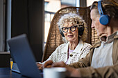 Älteres Ehepaar sitzt im Cafe und arbeitet an digitalem Tablet und Laptop